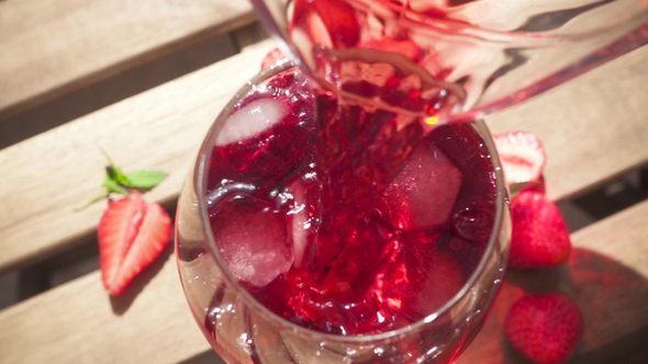 Red Drink Pours Into a Glass on the Table