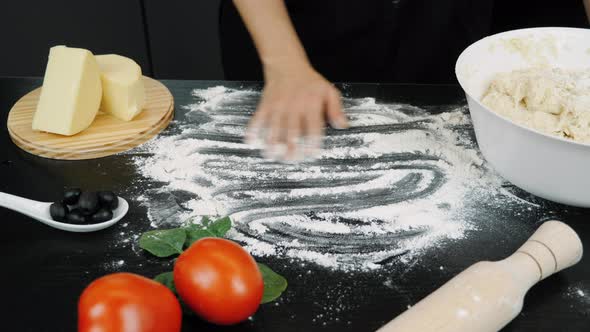 Cook's hand sprinkles flour on table. Pizza cooking alt