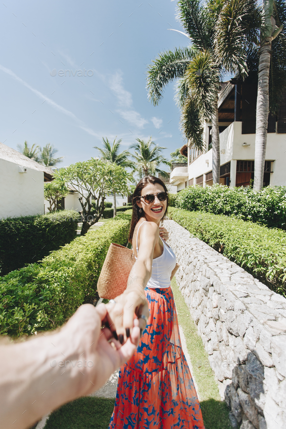 Husband following his wife on a vacation - Stock Photo - Images