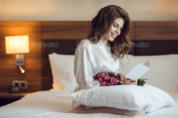 Smiling woman with bouquet in the hotel Stock Photo by AboutImages