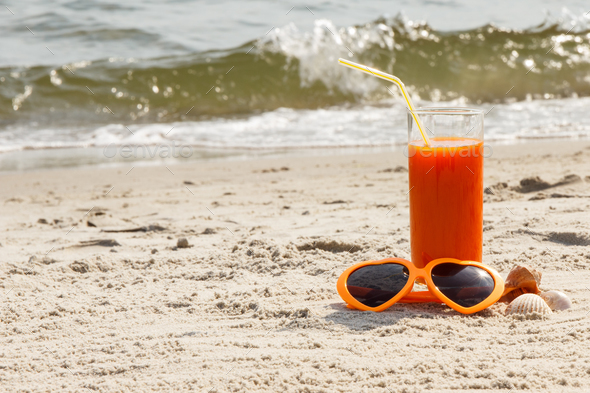 Carrot juice and sunglasses at beach, concept of vitamin A and beautiful, lasting tan - Stock Photo - Images