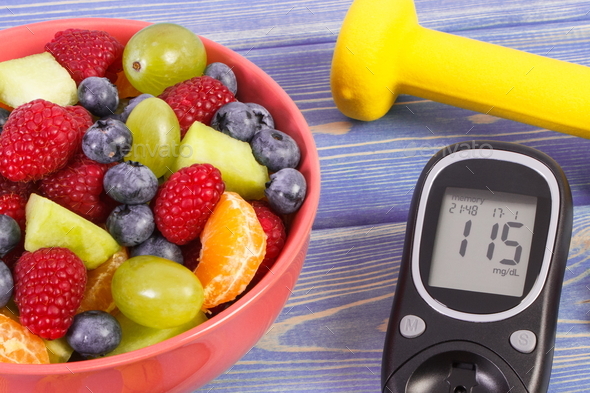 Fruit salad, glucometer for checking sugar level and dumbbells - Stock Photo - Images