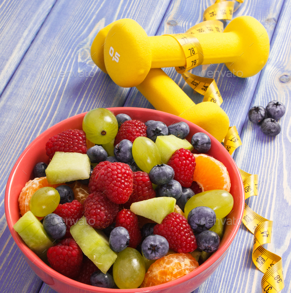 Fruit salad and centimeter with dumbbells, healthy lifestyle and nutrition concept - Stock Photo - Images