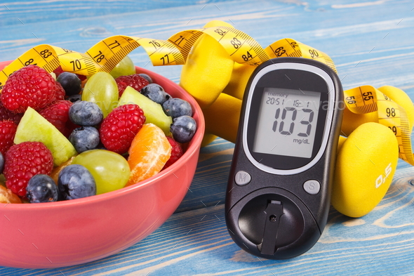 Fruit salad, glucose meter, centimeter and dumbbells - Stock Photo - Images