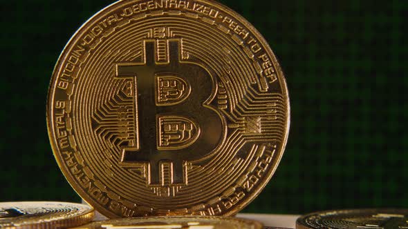 Bitcoin cryptocurrency gold coin close-up. There are green numbers running in the background alt