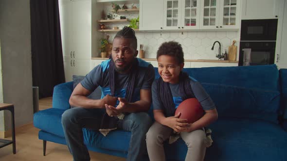 Joyful African American Boy with Father Celebrating First Down with Football alt