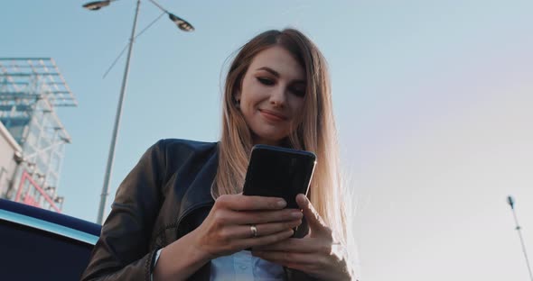 Excited Young Woman Holding Phone Chat in Dating App Feels Happy Standing on the alt