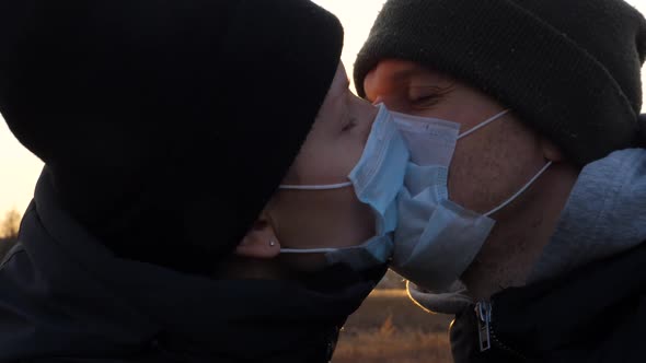 Young Couple Wearing Protective Face Masks And Kissing Outdoors.  alt