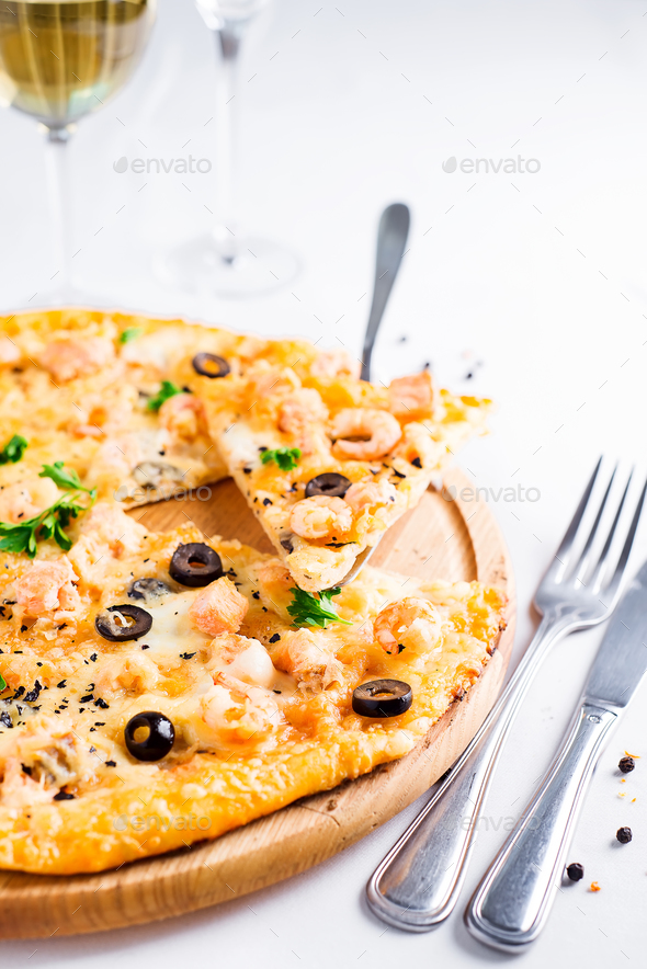 Fresh baked pizza hawaii with with pineapple, salmon and shrimp on wooden plate Stock Photo by lyulkamazur