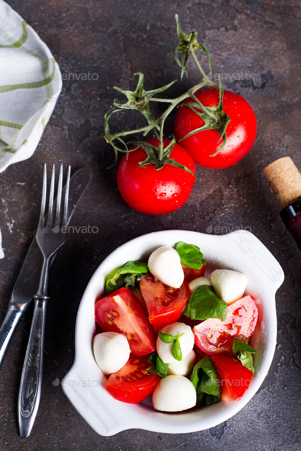 Caprese salad with mozzarella, tomato, basil and balsamic vinegar arranged on white bowl - Stock Photo - Images