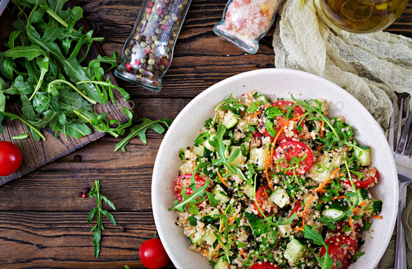 Salads with quinoa, arugula, radish, tomatoes and cucumber in bowl on wooden background. - Stock Photo - Images