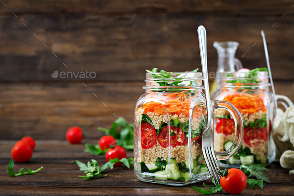 Salads with quinoa, arugula, radish, tomatoes and cucumber in glass jars on wooden background. - Stock Photo - Images