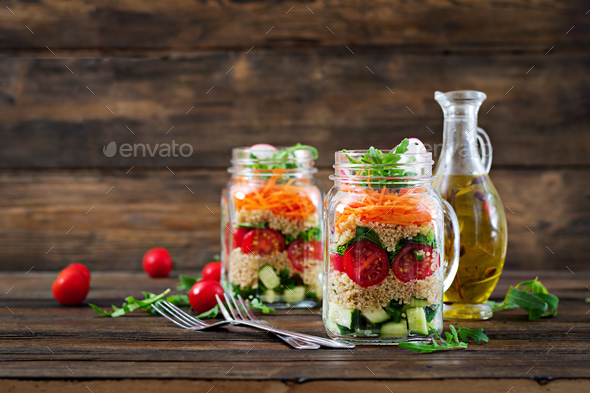 Salads with quinoa, arugula, radish, tomatoes and cucumber in glass jars - Stock Photo - Images