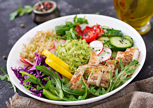 Buddha bowl lunch with grilled chicken and quinoa, tomato, guacamole, red cabbage, cucumber - Stock Photo - Images