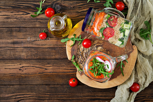 Salads with quinoa, arugula, radish, tomatoes and cucumber in glass jars - Stock Photo - Images