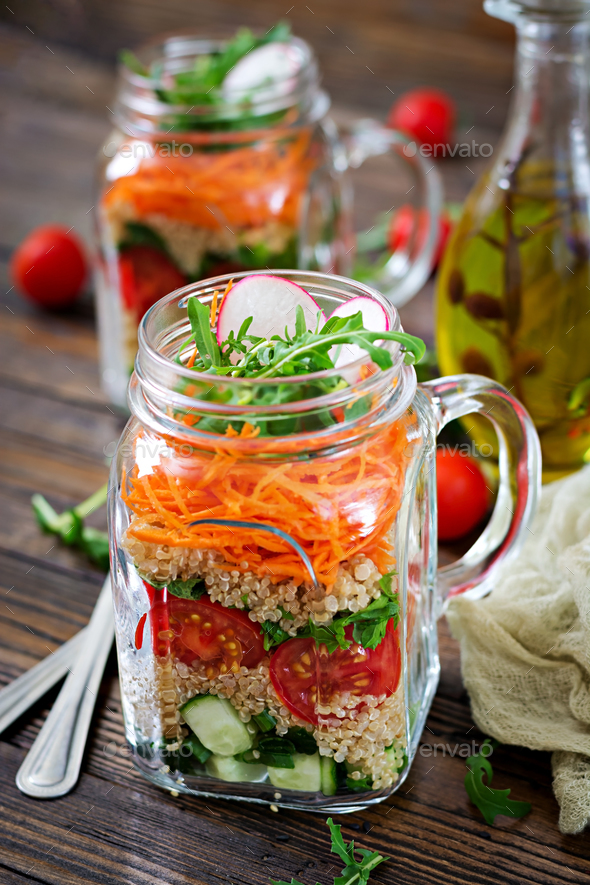 Salads with quinoa, arugula, radish, tomatoes and cucumber in glass jars on wooden background. - Stock Photo - Images