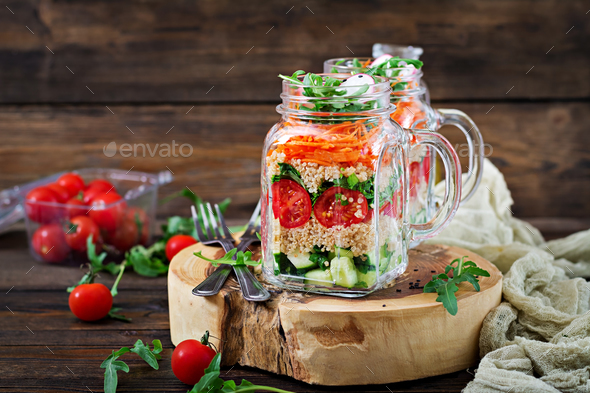Salads with quinoa, arugula, radish, tomatoes and cucumber in glass jars - Stock Photo - Images