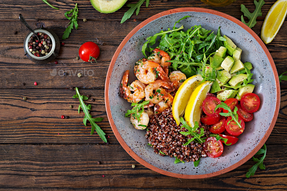 Delicious healthy Buddha bowl with shrimps, tomato, avocado, quinoa, lemon and arugula - Stock Photo - Images