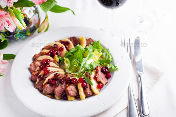 Salad with slices of duck breast with apples and salad under cowberry sauce - Stock Photo - Images