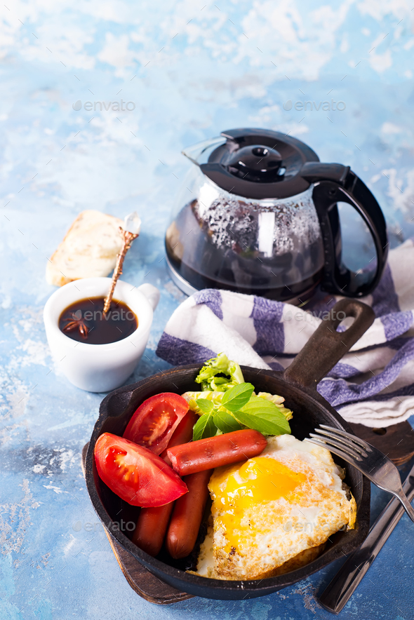 Homemade delicious breakfast on a pan with fried egg, toast, sausage, vegetable, black coffee - Stock Photo - Images