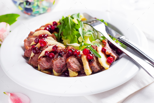 Salad with slices of duck breast with apples and salad under cowberry sauce - Stock Photo - Images