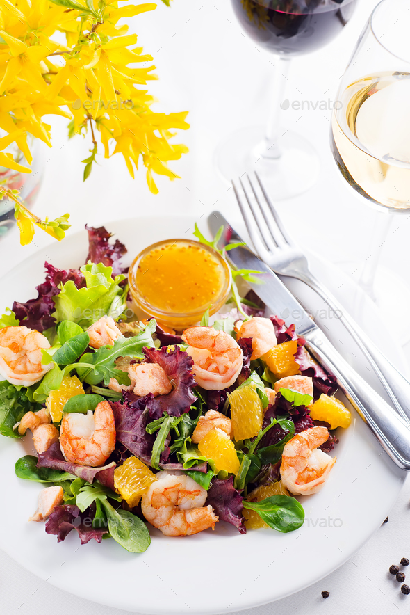 Healthy salad with prawns, lettuce, oranges and mango served on a plate with orange mustard sauce - Stock Photo - Images