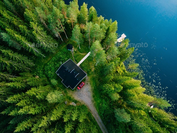 Aerial view of wooden cottage in green forest by the blue lake in rural summer Finland - Stock Photo - Images