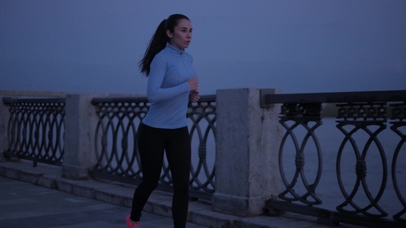 A Young Girl in Sports Clothes Jogging on the Waterfront in the Moonlight