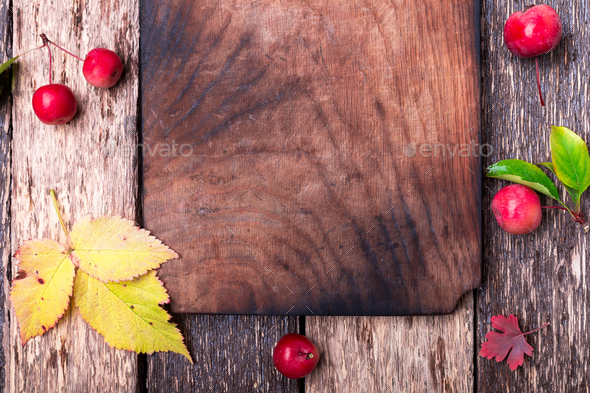 Leaves and small apple around empty cutting board - Stock Photo - Images