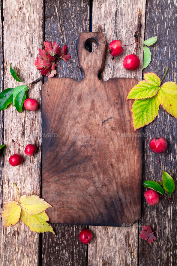 Leaves and small apple around empty cutting board - Stock Photo - Images
