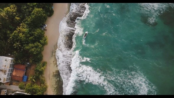 Aerial Flyover Drone Shot of Idyllic Exotic Sea Shore with Little Boat, Foaming White Crashing Waves alt