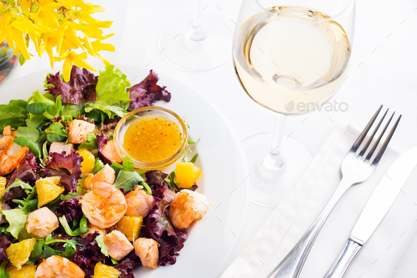 Healthy salad with prawns, lettuce, oranges and mango served on a plate with orange mustard sauce - Stock Photo - Images