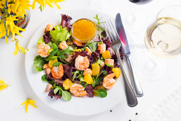 Healthy salad with prawns, lettuce, oranges and mango served on a plate with orange mustard sauce - Stock Photo - Images