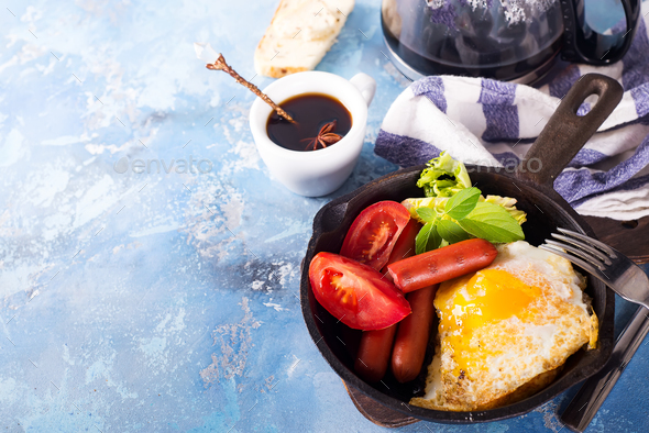 Homemade delicious breakfast on a pan with fried egg, toast, sausage, vegetable, black coffee - Stock Photo - Images