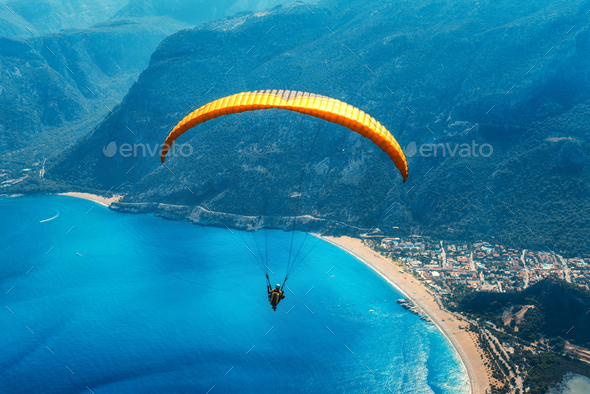 Paraglider tandem flying over the sea with blue water and mountains - Stock Photo - Images
