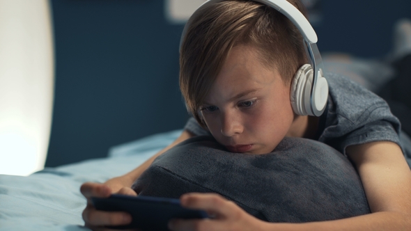 Boy Playing Smartphone on Bed alt