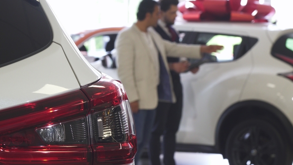 Professional Car Salesman Showing Cars for Sale To His Male Customer alt