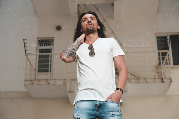 Stylish bearded man with long hair and tattoos posing - Stock Photo - Images