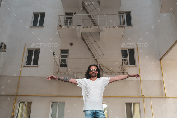 Stylish bearded man with long hair and tattoos posing holding ar - Stock Photo - Images