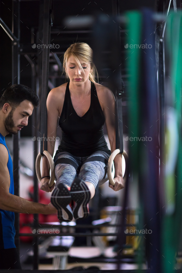 woman working out with personal trainer on gymnastic rings Stock Photo by dotshock