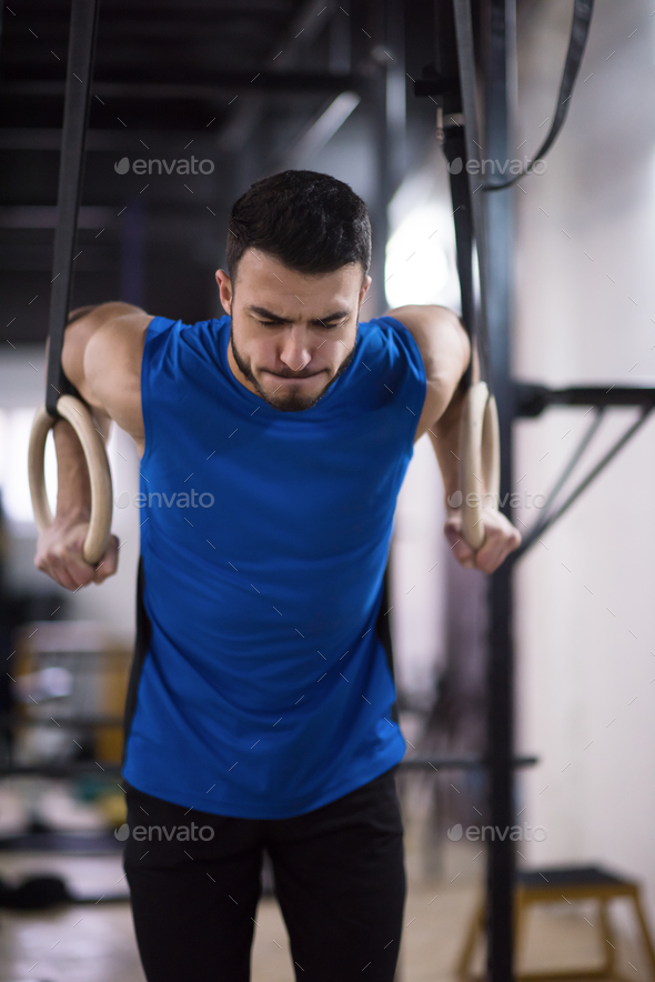 man working out pull ups with gymnastic rings Stock Photo by dotshock