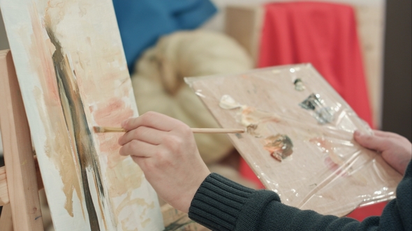 Male Artist Hands Applying Brush Strokes on Canvas and Holding Palette alt