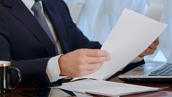 Businessman Signing Documents with a Cup of Coffee on the Table alt
