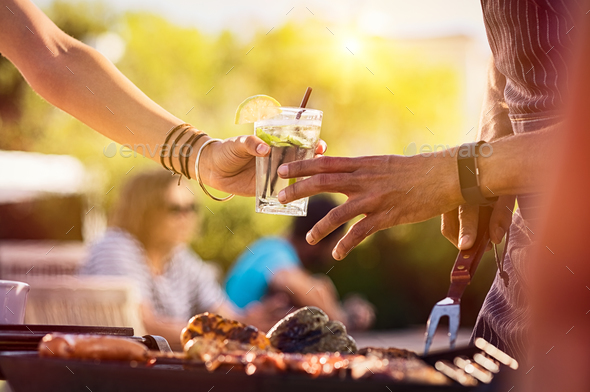 Woman sharing drink at bbq - Stock Photo - Images