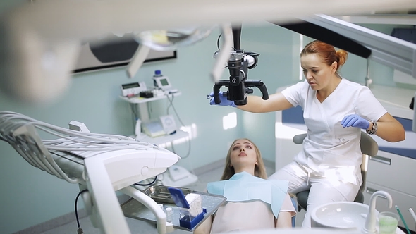 Female Dentist with Dental Tools - Microscope, Mirror and Probe Treating Patient Teeth at Dental