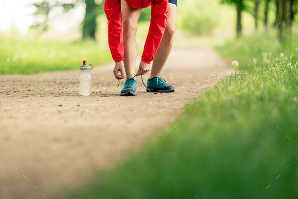 Woman runner tying sport shoes in summer park - Stock Photo - Images