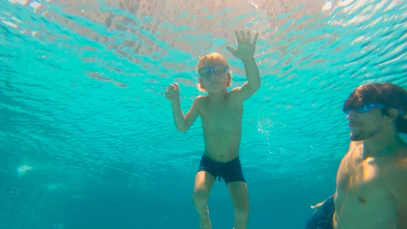 Underwater Shot of Father and His Toddler Son Swining Diving and Having