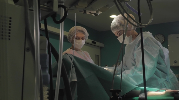 Surgeon and Surgical Team Are Performing Cosmetic Surgery on Breasts in Hospital Operating Room