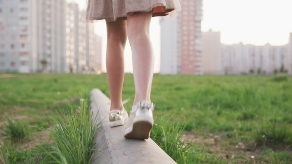 Legs of Little Girl Walking on Concrete Log on Urban Lawn