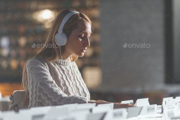 Attractive girl browsing records in a music store Stock Photo by AboutImages